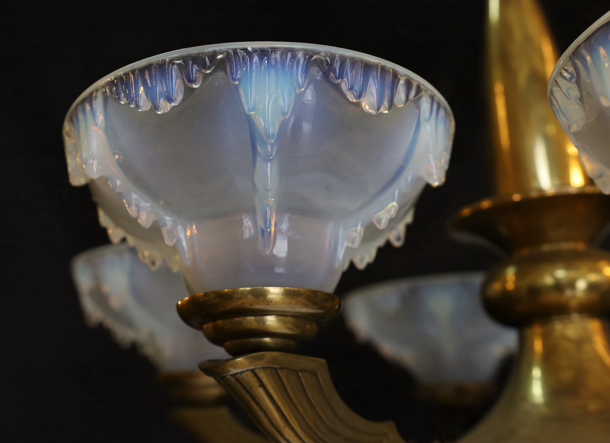 A French Art Deco bronze and opalescent glass six light chandelier by Ezan, with scrolling branches and ‘melting ice‘ shades, height 80cm. width 70cm